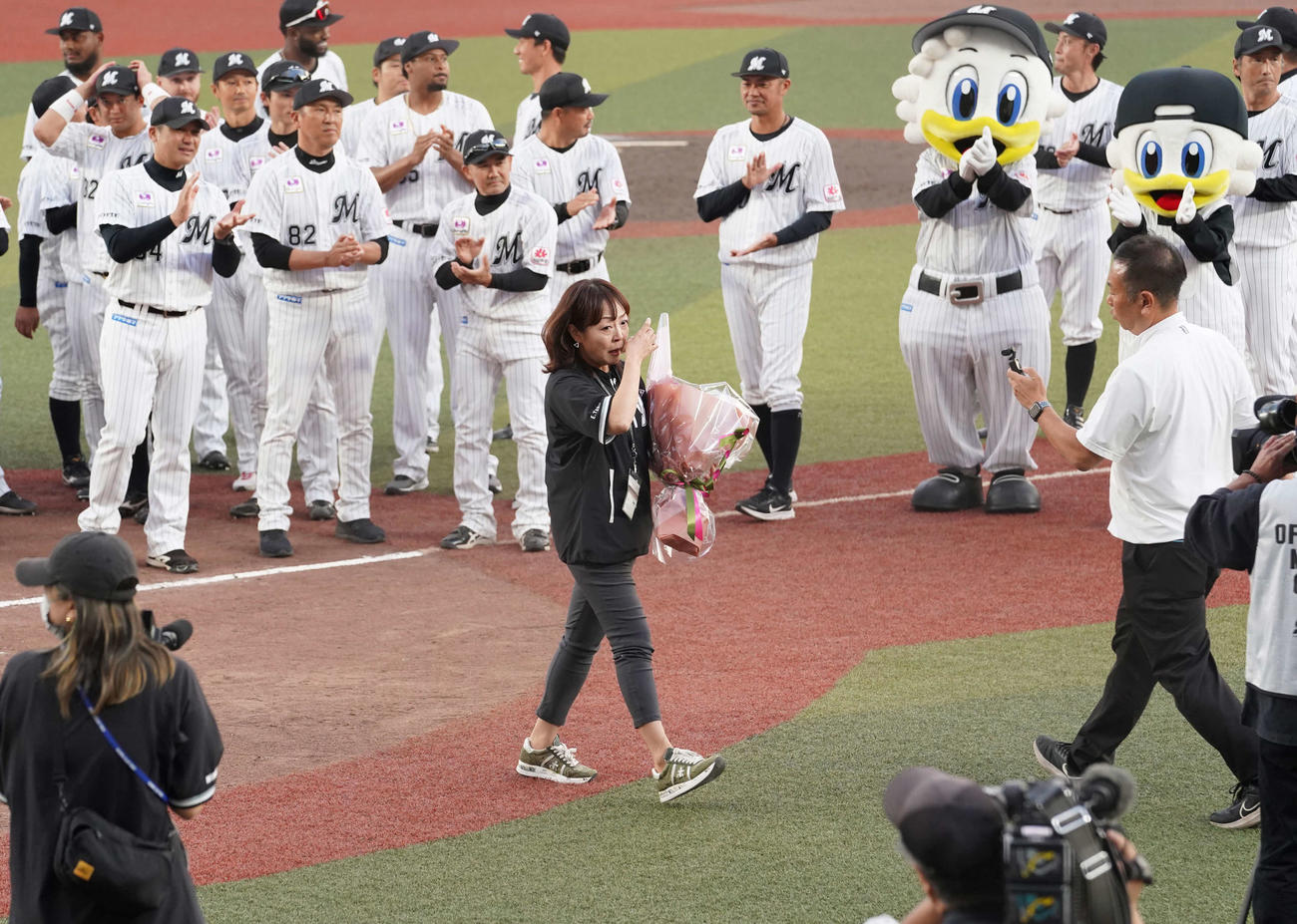 ロッテ対オリックス　今季限りでの引退を発表したZOZOマリンスタジアム場内アナウンス担当の谷保さん（中央）はナインとの記念撮影を終え感極まる（撮影・小沢裕）