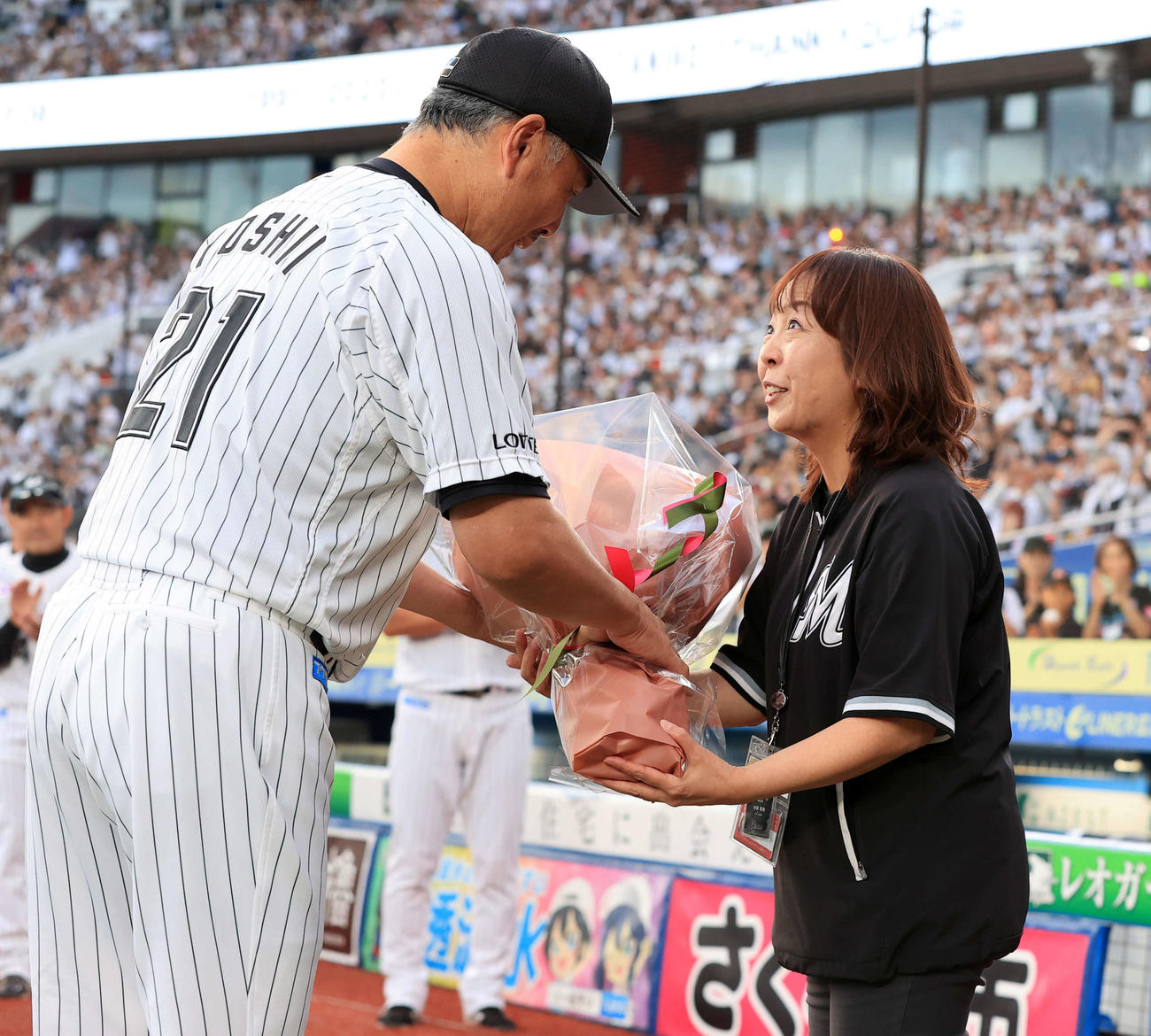 ロッテ対オリックス　今季限りで場内アナウンサーから卒業する谷保恵美さん（右）は、ロッテ吉井監督から花束を贈られる（撮影・浅見桂子）