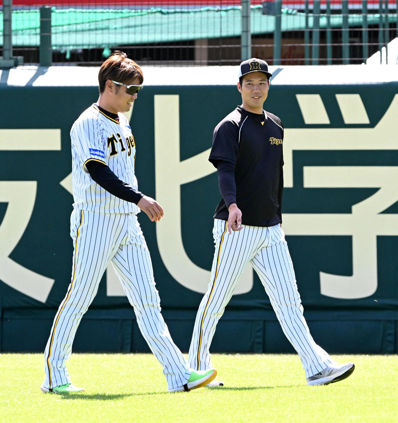 外野を歩きながら笑顔で話す西勇（左）と青柳（撮影・前岡正明）