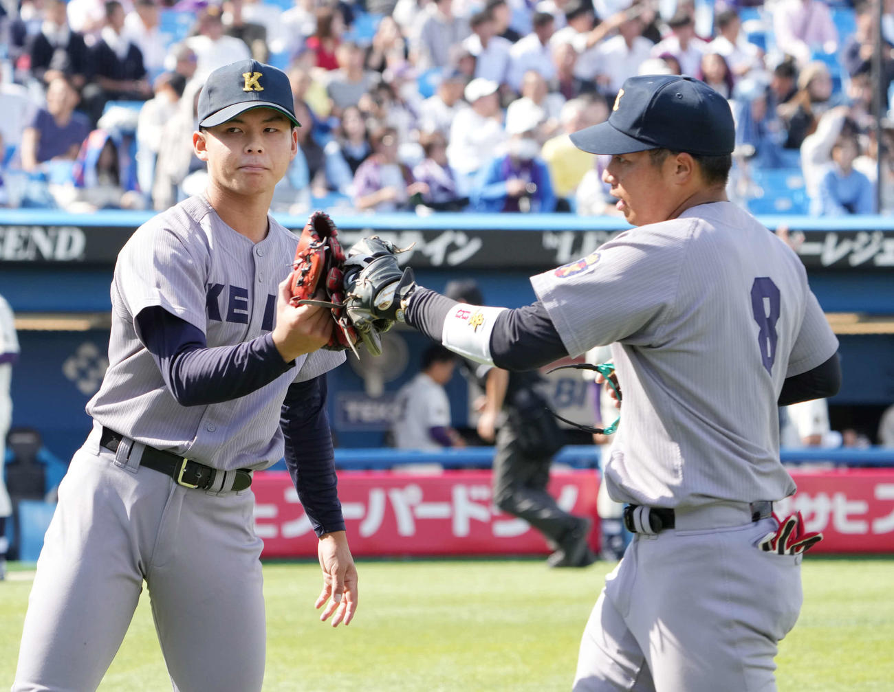 明大対慶大　8回表明大2死、慶大先発の外丸（左）は栗林泰とグラブタッチ（撮影・小沢裕）