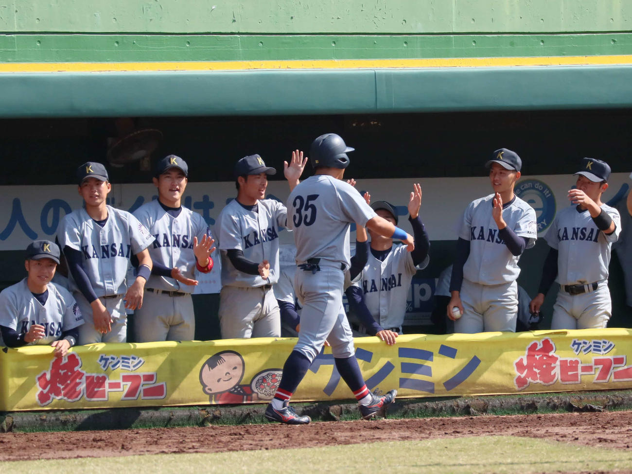 2回6番下井田の左適時打で生還した富山を迎える関大ナイン（撮影・村松万里子）