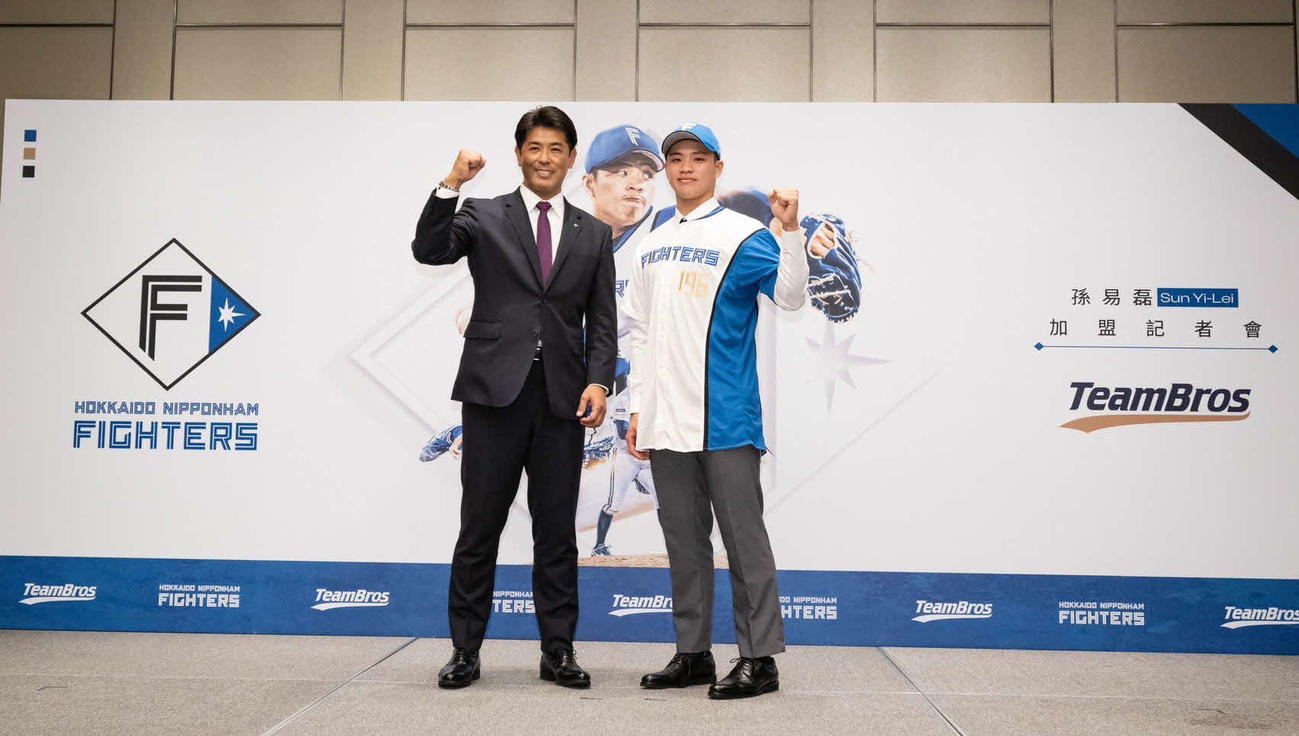 日本ハムの入団会見でポーズを取る孫易磊（右）と稲葉GM（球団提供）