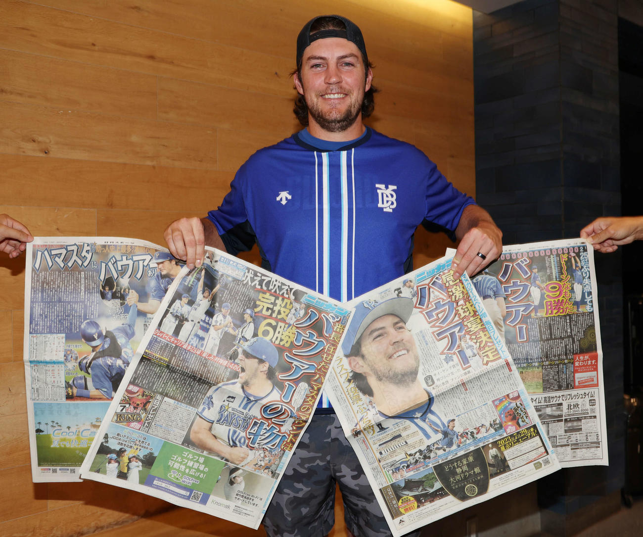 会見で今季紙面を飾った日刊スポーツを手に笑顔を見せるDeNAバウアー（撮影・野上伸悟）