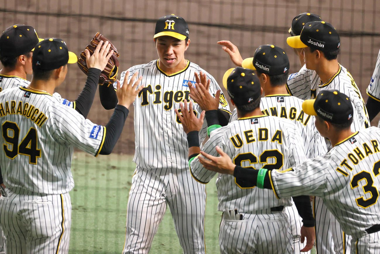 CSファイナル　阪神対広島　8回、阪神3番手で登板した石井（左から3人目）は2者を抑え交代となりナインの祝福に笑顔を見せる（撮影・上山淳一）