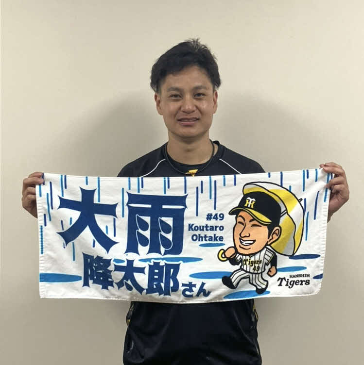 「大雨耕太郎さん」フェイスタオルを持つ、阪神大竹（球団提供）