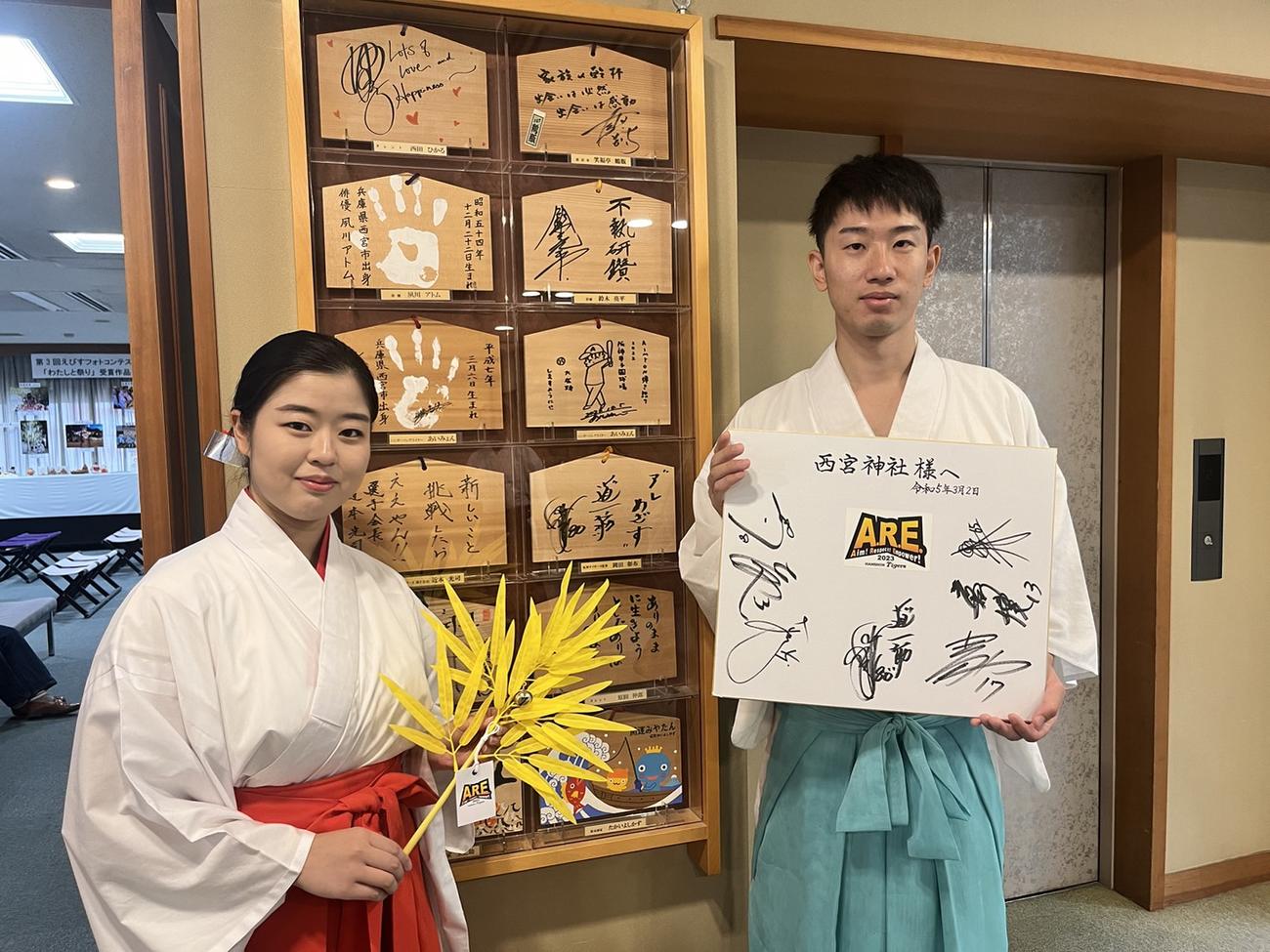タイガースオリジナル福笹を手にする西宮神社の巫女さん（左）と岡田監督や選手のサインが入った色紙を手にする小嶋今晨さん（撮影・中野椋）