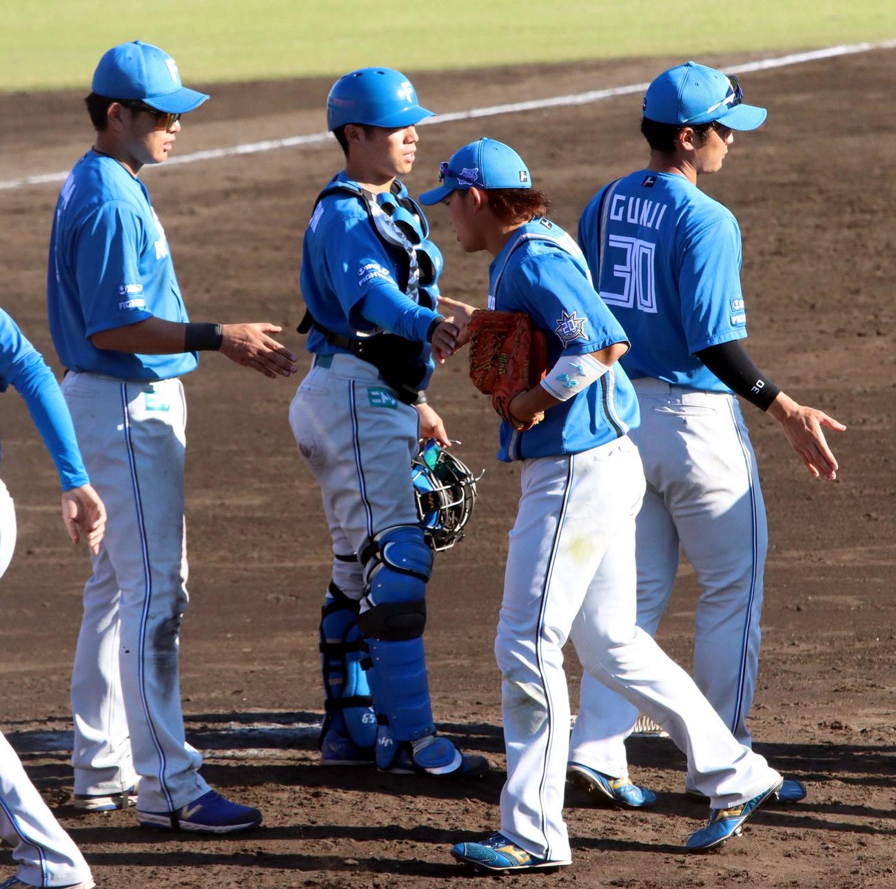 楽天対日本ハム　勝利を挙げチームメートとタッチする日本ハム梅林（中央）（撮影・永野高輔）