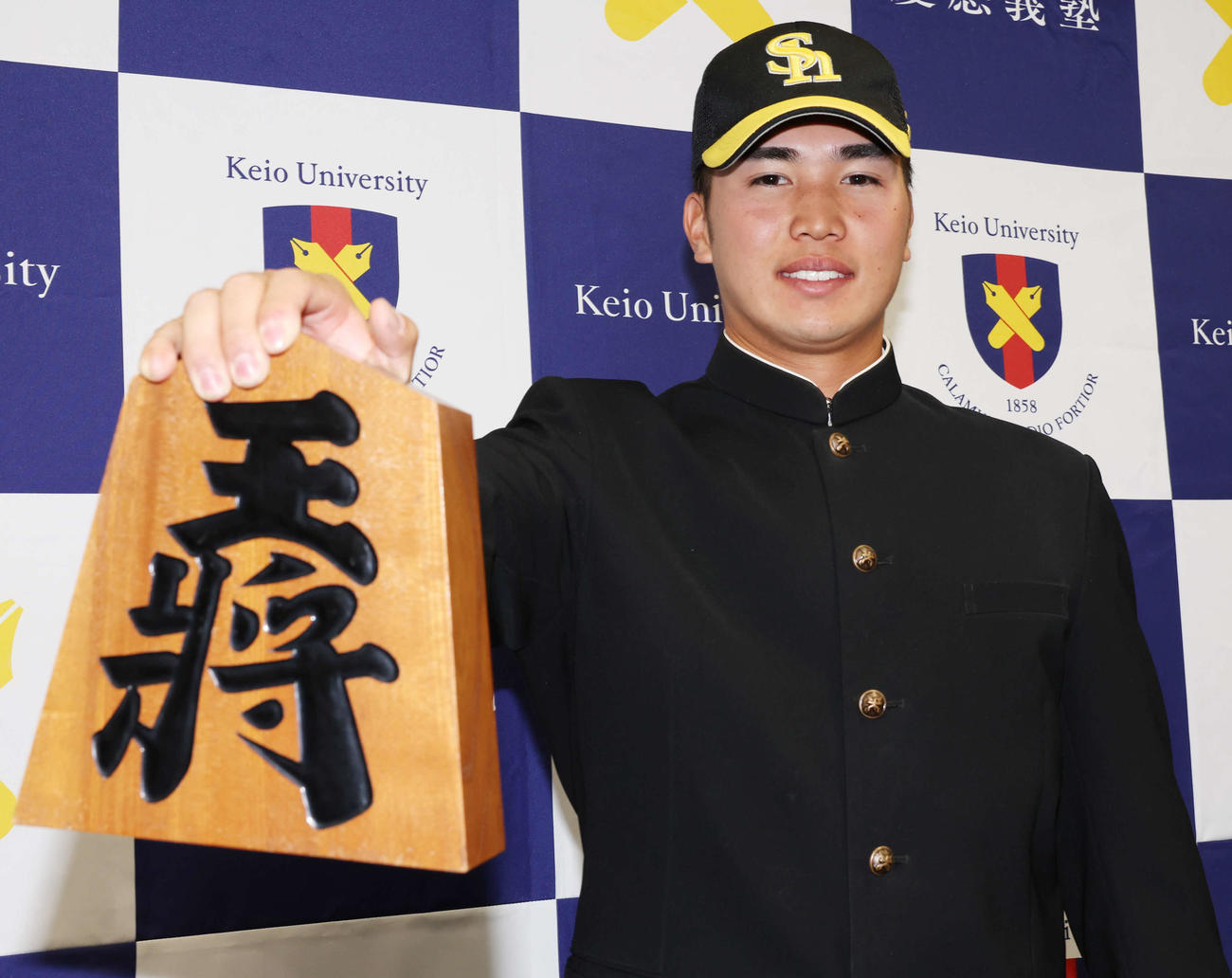 ソフトバンクから3位指名を受けた慶大・広瀬は、「陸の王者」らしく王将の駒を手に笑顔（撮影・野上伸悟）