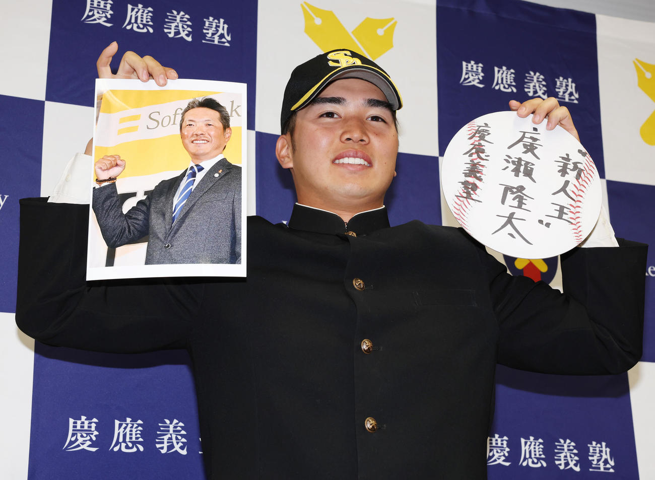 ソフトバンクから3位指名を受け小久保裕紀監督の写真と、新人王と書いたボードを手に笑顔の慶大・広瀬隆（撮影・野上伸悟）