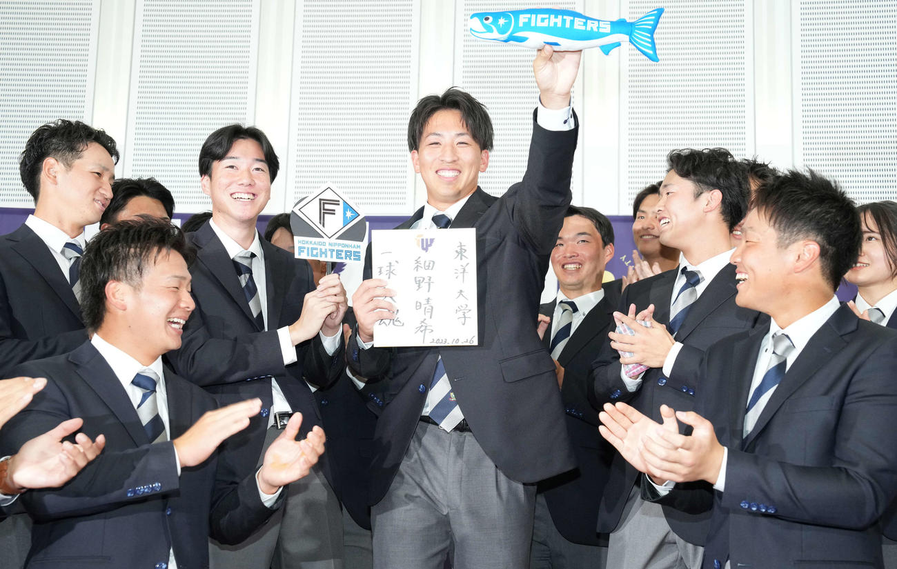 日本ハムにドラフト1位で指名された東洋大・細野（中央）はしゃけまるを手に笑顔（撮影・鈴木みどり）