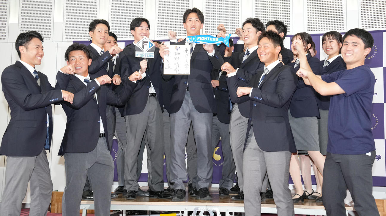日本ハムにドラフト1位で指名された東洋大・細野（中央）はしゃけまるを手に笑顔（撮影・鈴木みどり）