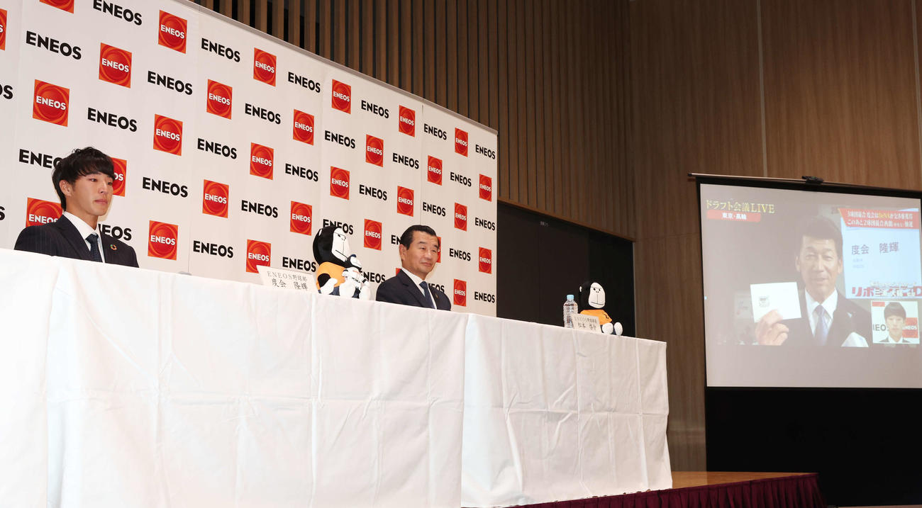 DeNAから1位指名を受け涙を見せるENEOS・度会（左）。右はスクリーンに映る交渉権を獲得した三浦監督（撮影・宮地輝）