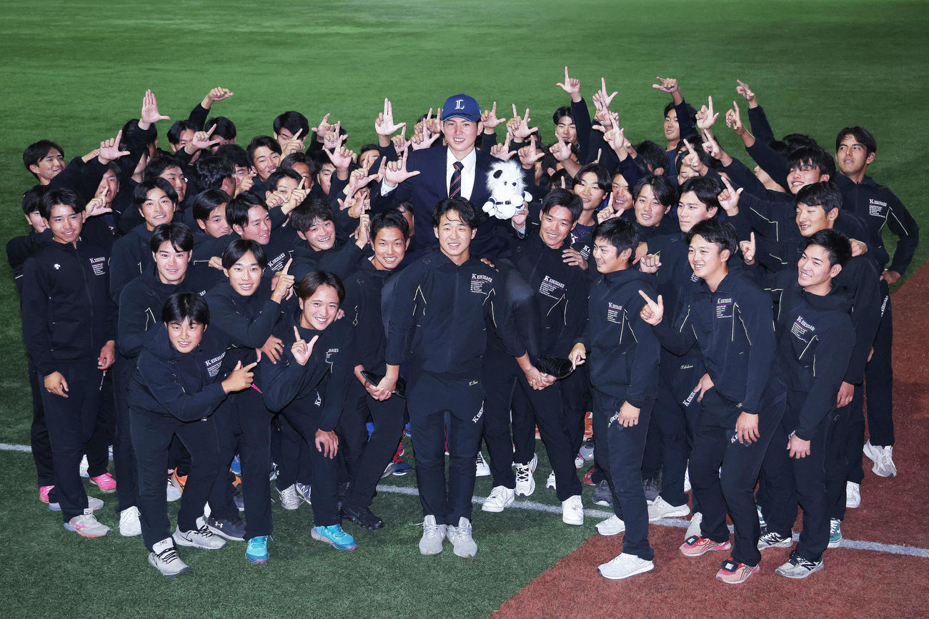 西武1位指名を受け、仲間と「L」ポーズを決め写真に納まる国学院大・武内（中央）（撮影・河田真司）