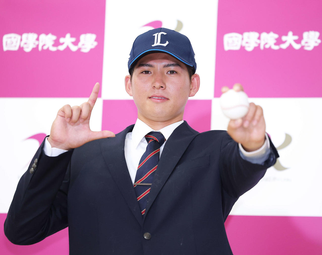西武1位指名を受け、「L」ポーズで写真に納まる国学院大・武内（撮影・河田真司）