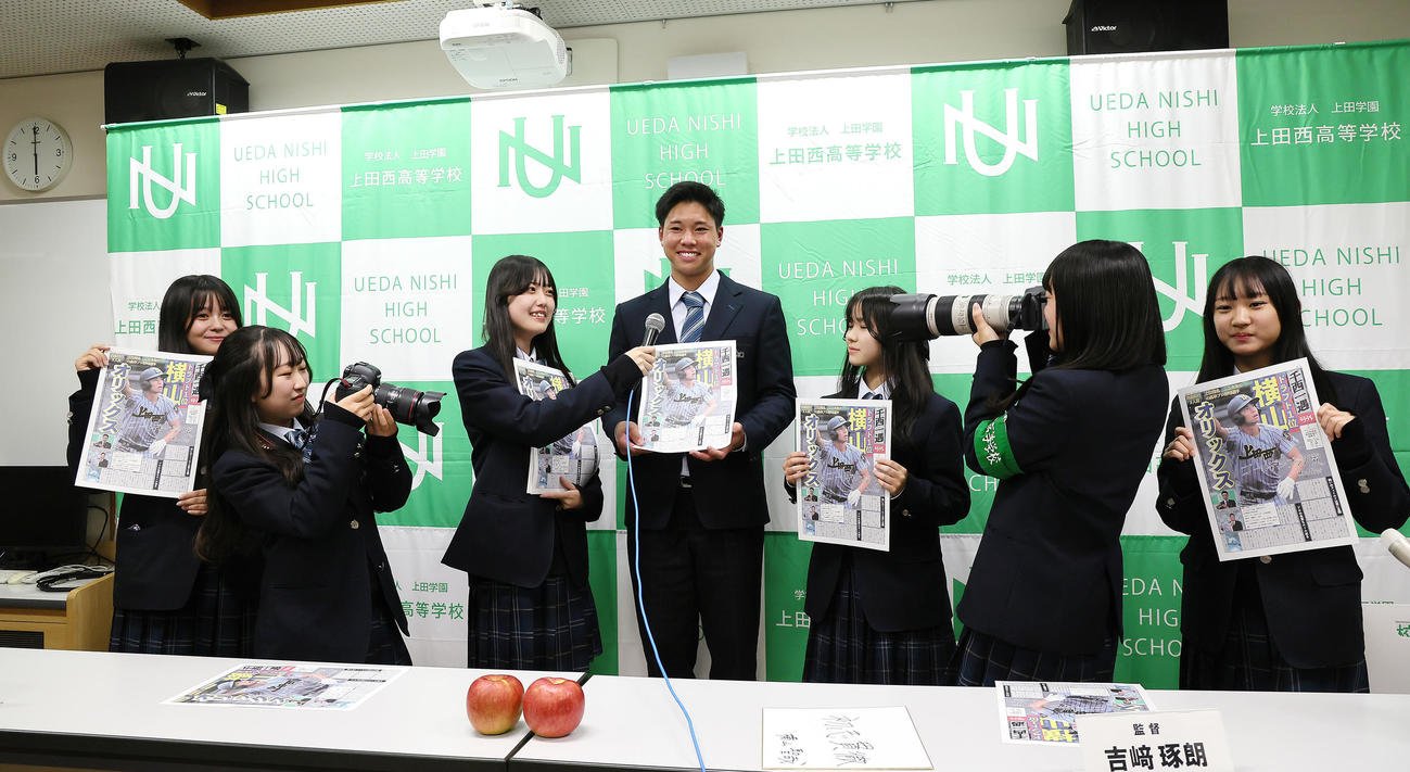 オリックスに1位指名された上田西・横山（中央）は新聞委員会の号外を手に笑顔を見せる（撮影・足立雅史）