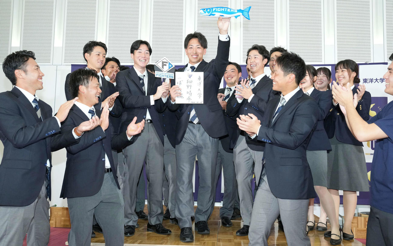 日本ハムにドラフト1位で指名された東洋大・細野（中央）はしゃけまるを手に笑顔（撮影・鈴木みどり）