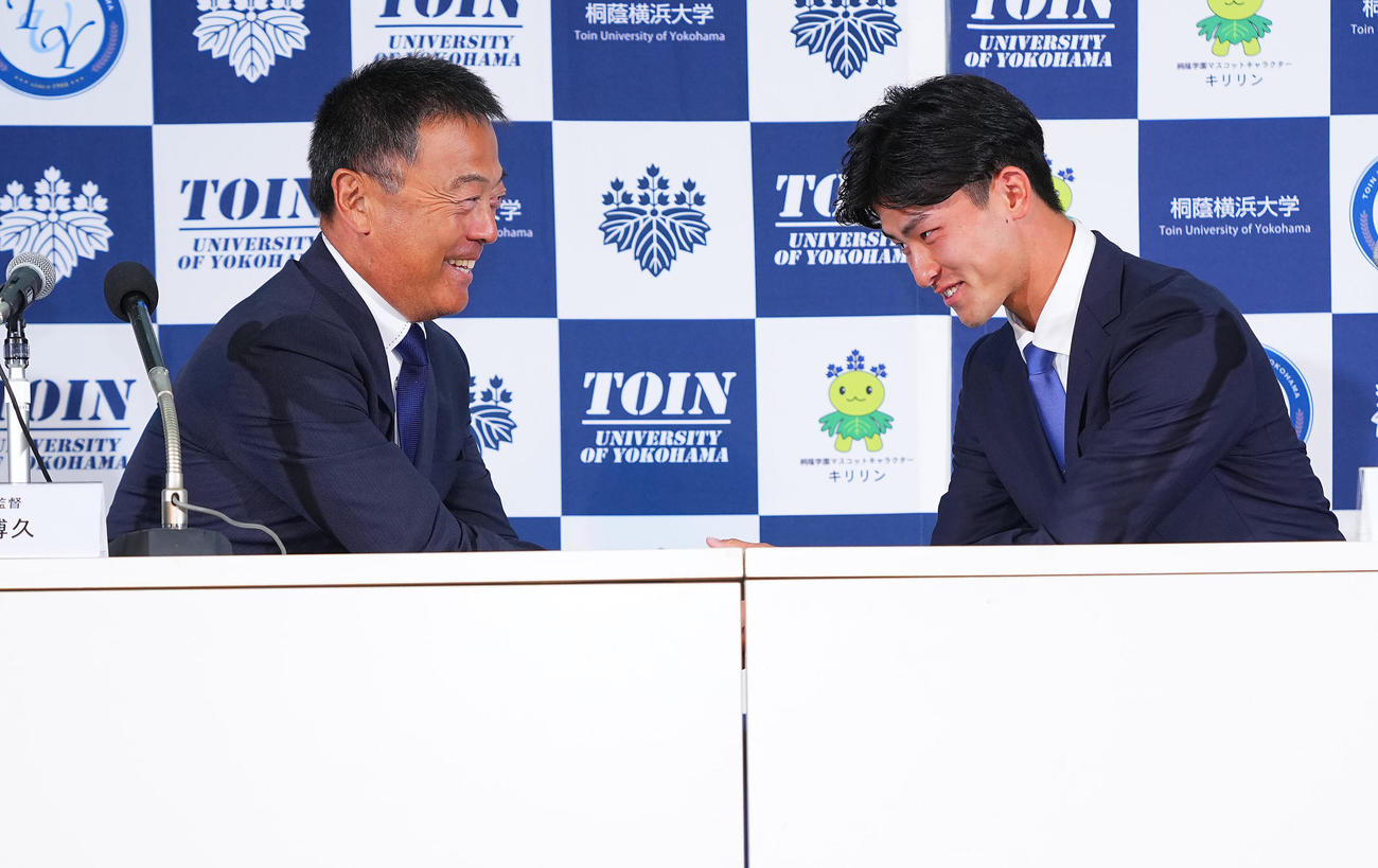 楽天から1位指名を受けた桐蔭横浜大・古謝（右）は机の下で握手を交わす斉藤監督（撮影・垰建太）