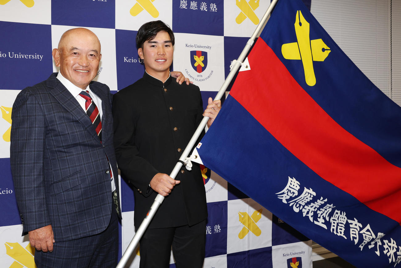 ソフトバンクから3位指名を受けた慶大・広瀬（右）は、部旗を手に堀井監督と笑顔（撮影・野上伸悟）