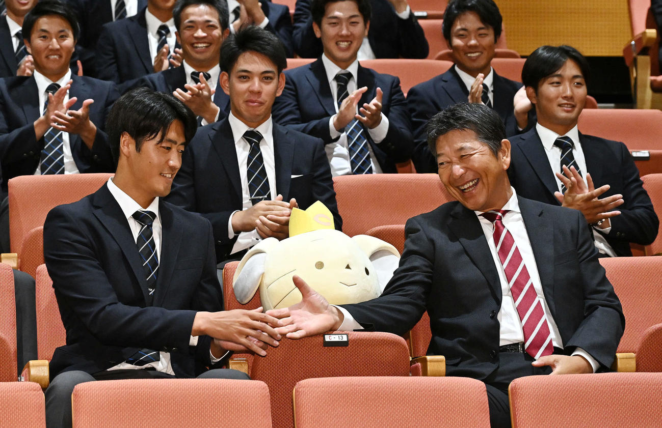 巨人からドラフト1位で指名された中大・西舘（手前左）は清水監督と握手を交わす（撮影・滝沢徹郎）