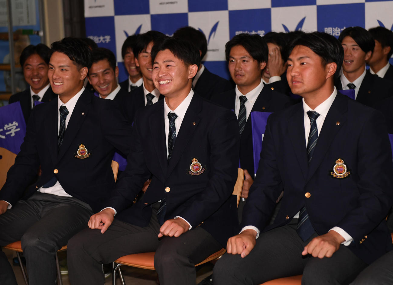 ヤクルト3位指名に明大・石原勇輝（中央）は笑顔を見せる。右はソフトバンク4位指名の村田賢一（撮影・柴田隆二）