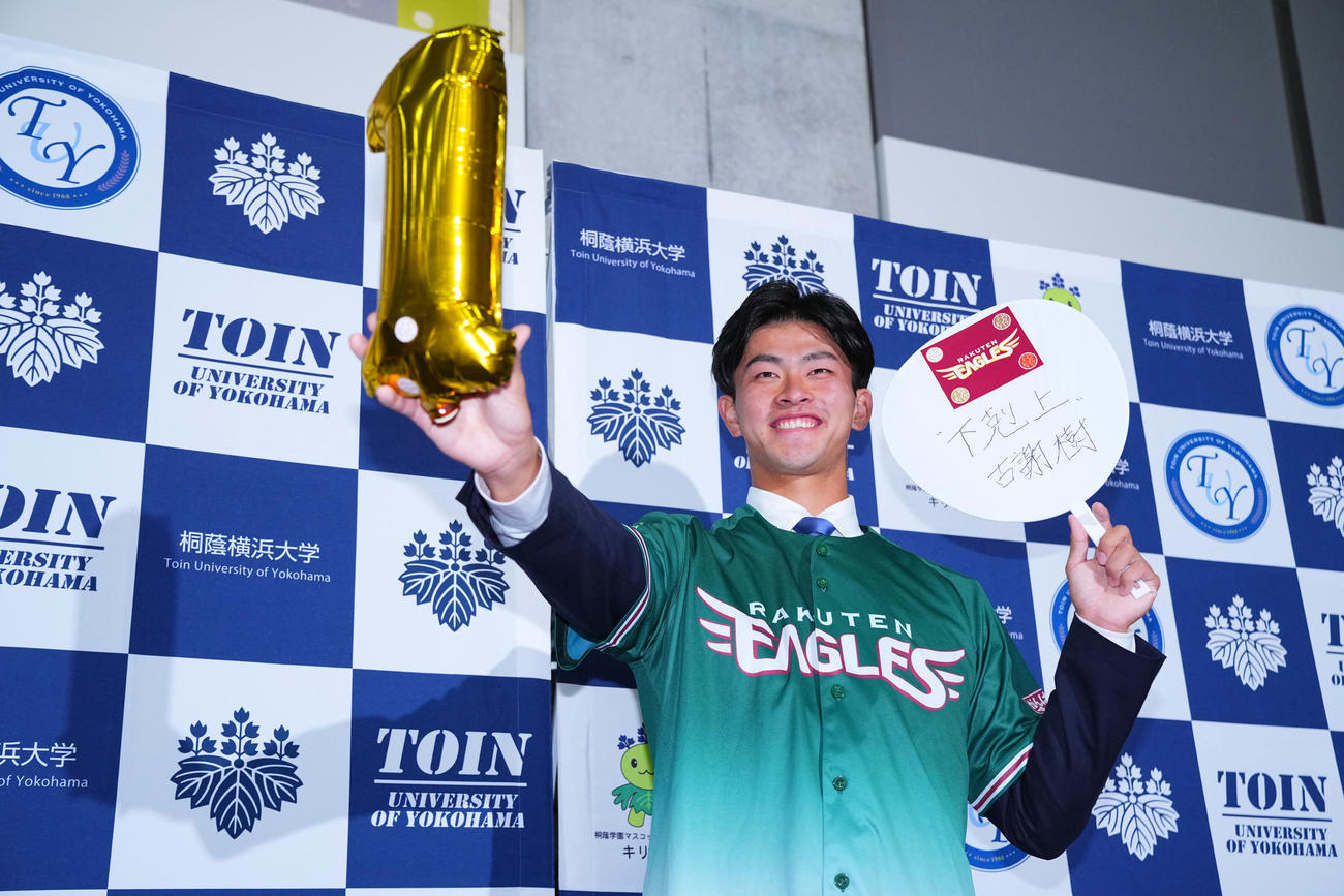 楽天から1位指名を受けた桐蔭横浜大・古謝は「下克上」の言葉を記し笑顔で写真に納まる（撮影・垰建太）