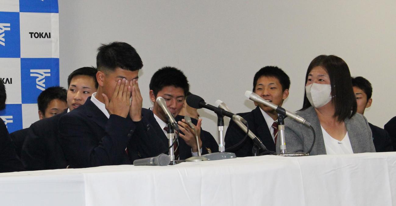 阪神4位指名で目頭を押さえる東海大熊本星翔の百崎蒼生内野手。右は母真由美さん（撮影・菊川光一）＝2023年10月26日、東海大熊本星翔