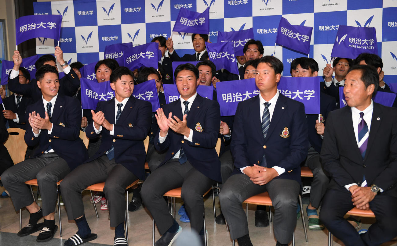 ロッテ1位指名された明大・上田希由翔（右から2人目）は仲間から祝福される。右端は田中監督