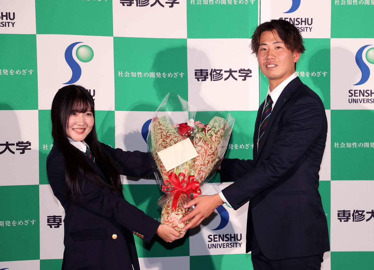 ヤクルト1位指名され花束を受け取る専大・西舘（右）（撮影・鈴木正人）
