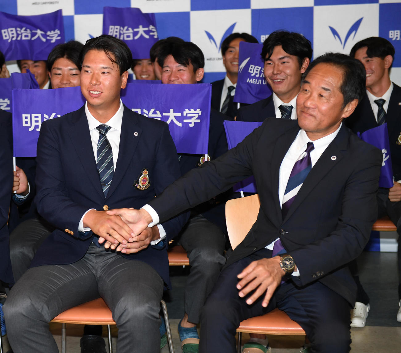 ロッテ1位指名に明大・上田希由翔（左）は田中監督と握手する（撮影・柴田隆二）