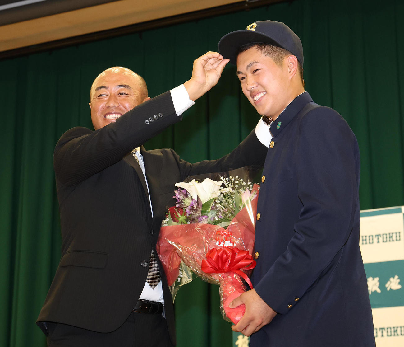オリックスから4位指名を受けて、大角監督（左）からオリックスの帽子をかぶせてもらう報徳学園・堀（撮影・白石智彦）