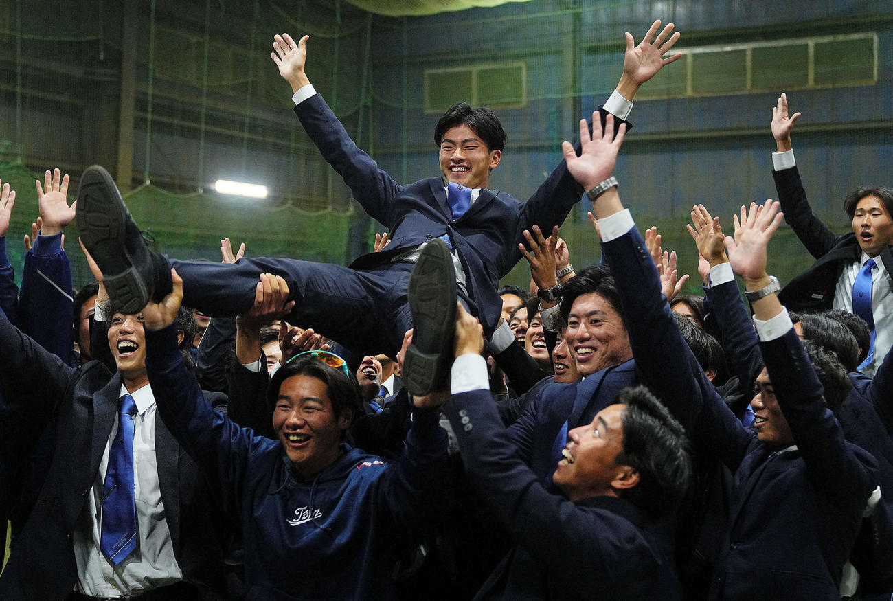 楽天から1位指名を受けた桐蔭横浜大・古謝（中央）はチームメートから胴上げされる（撮影・垰建太）