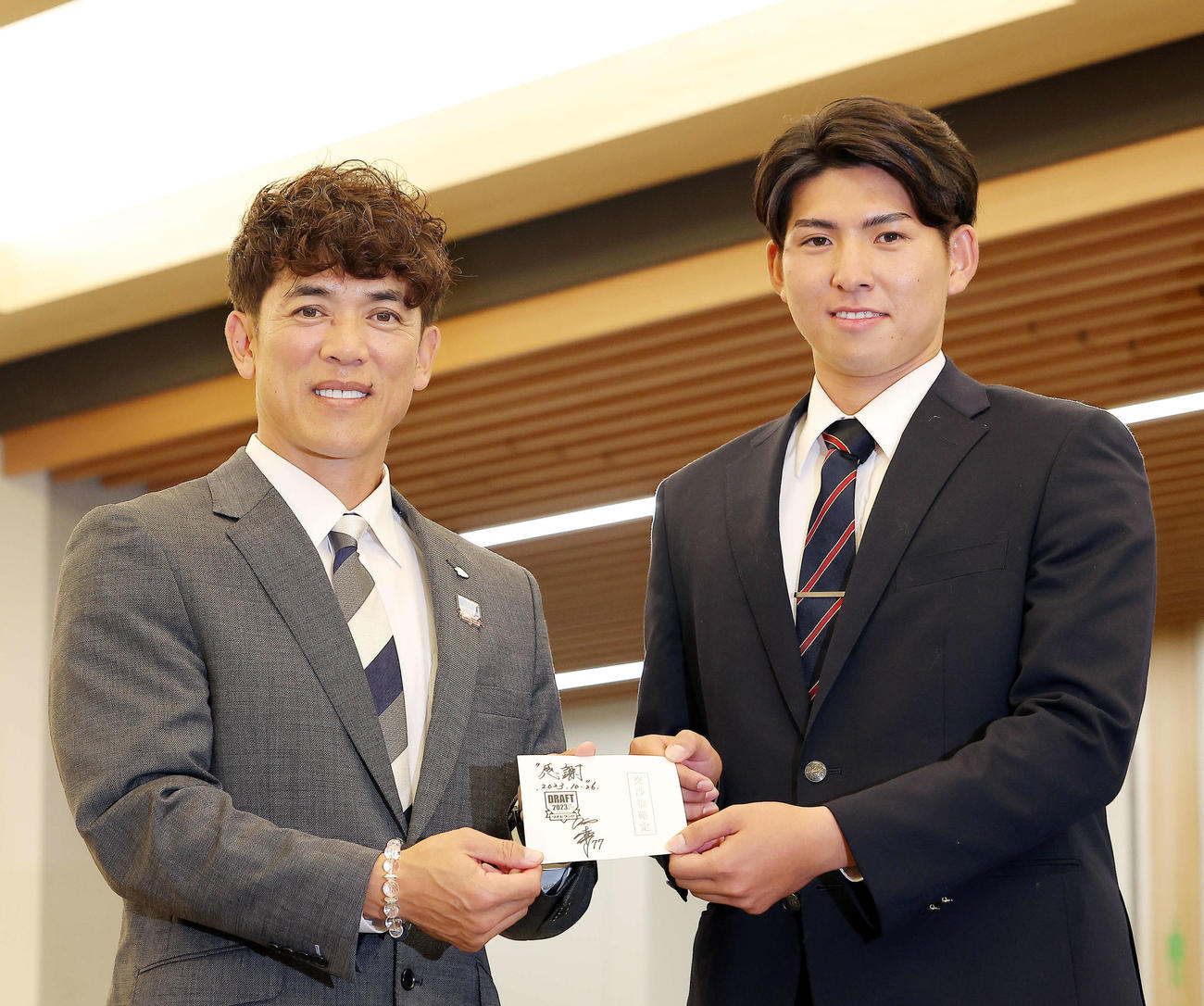 交渉権確定のくじを手に、笑顔を見せる西武松井監督（左）と1位指名の国学院大・武内（撮影・河田真司）