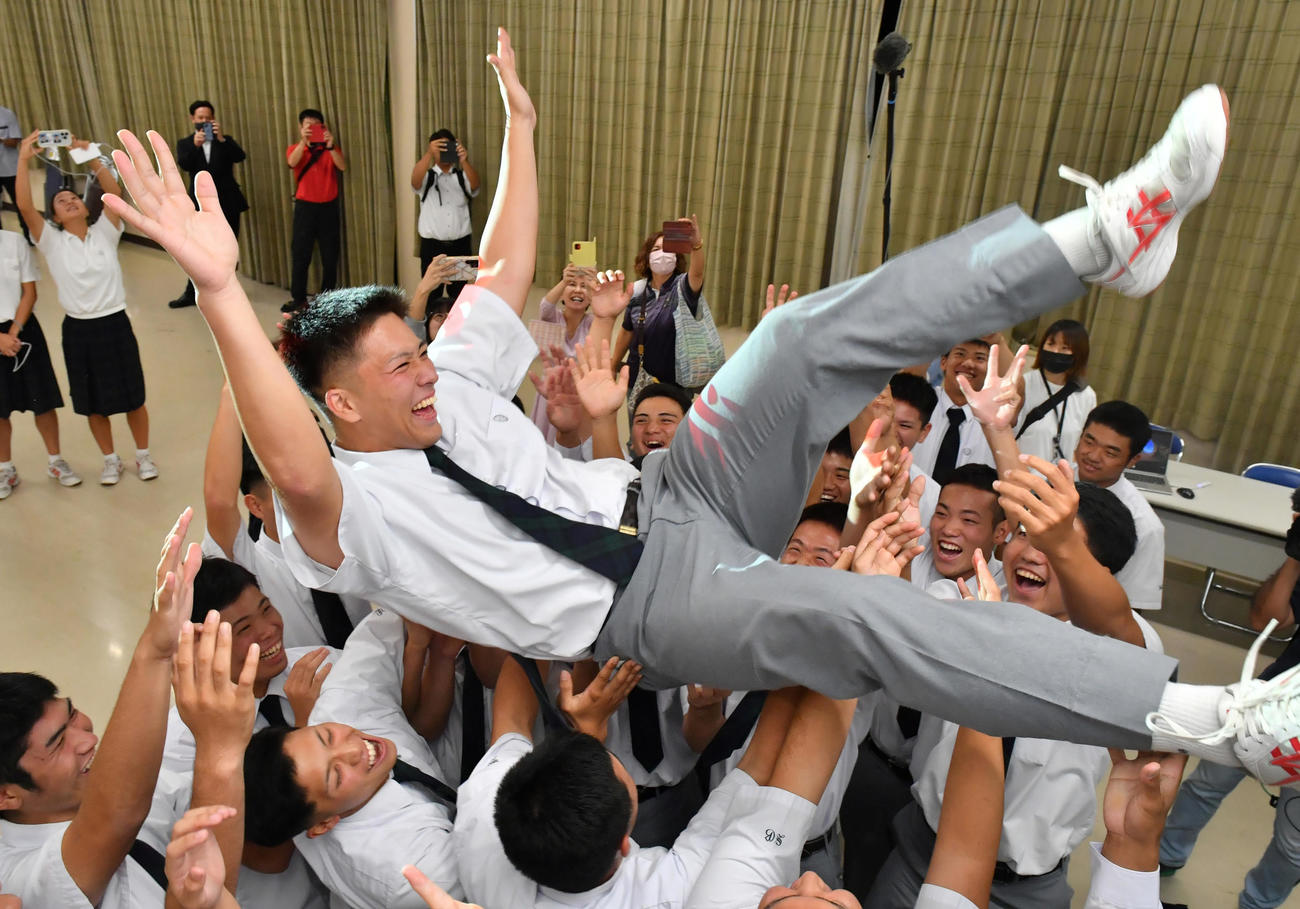 広島から4位指名を受け、同級生らから胴上げで祝福される沖縄尚学・仲田（沖縄タイムス提供）