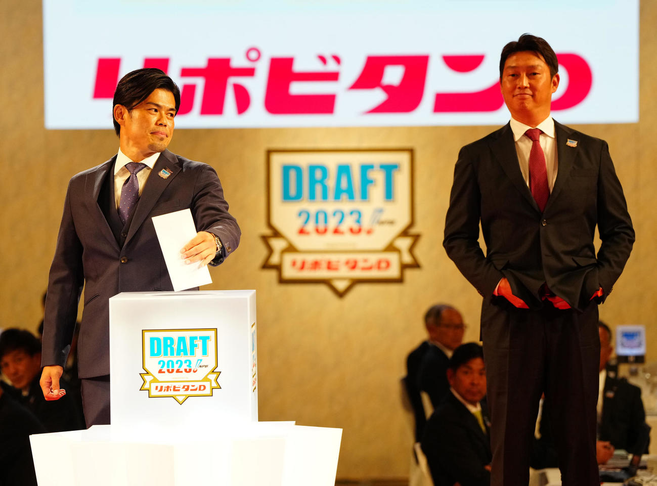 プロ野球ドラフト会議で青学大・常広を1位指名し、左手でくじを引く楽天今江監督（左）。右は広島新井監督（撮影・江口和貴）
