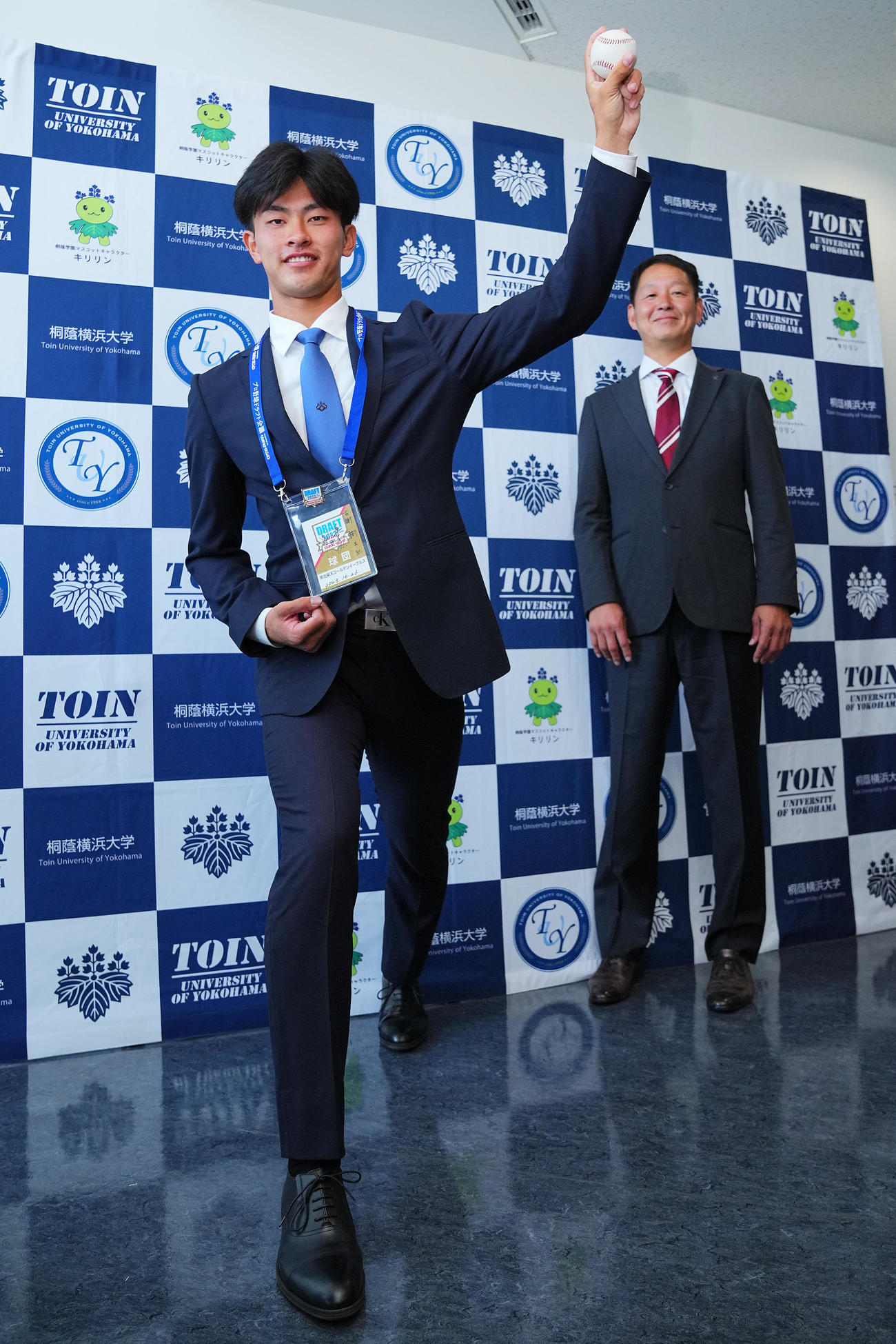 楽天1位の桐蔭横浜大・古謝（左）は指名あいさつを受け部坂スカウトらが見つめる中、笑顔で写真に納まる（撮影・垰建太）
