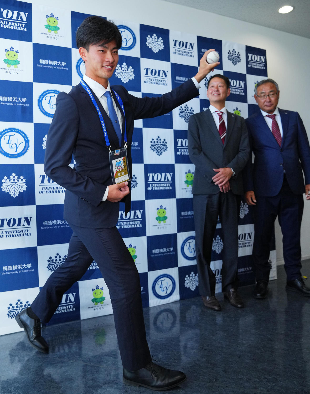 楽天1位の桐蔭横浜大・古謝（左）は指名あいさつを受けボールを手に写真に納まる。右から後関スカウト部長、部坂スカウト（撮影・垰建太）