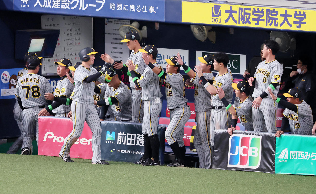 オリックス対阪神　5回表阪神2死三塁、三塁走者近本は中野の左適時打で生還しベンチのナインとタッチする（撮影・加藤哉）