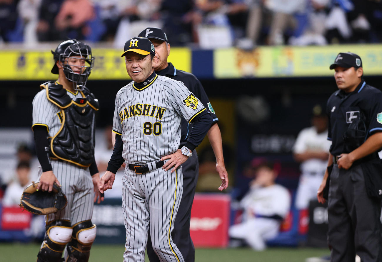オリックス対阪神　1回裏オリックス1死一塁、岡田監督（手前）は森のファウル判定に抗議するも変わらず苦笑いでベンチへ戻る（撮影・上山淳一）