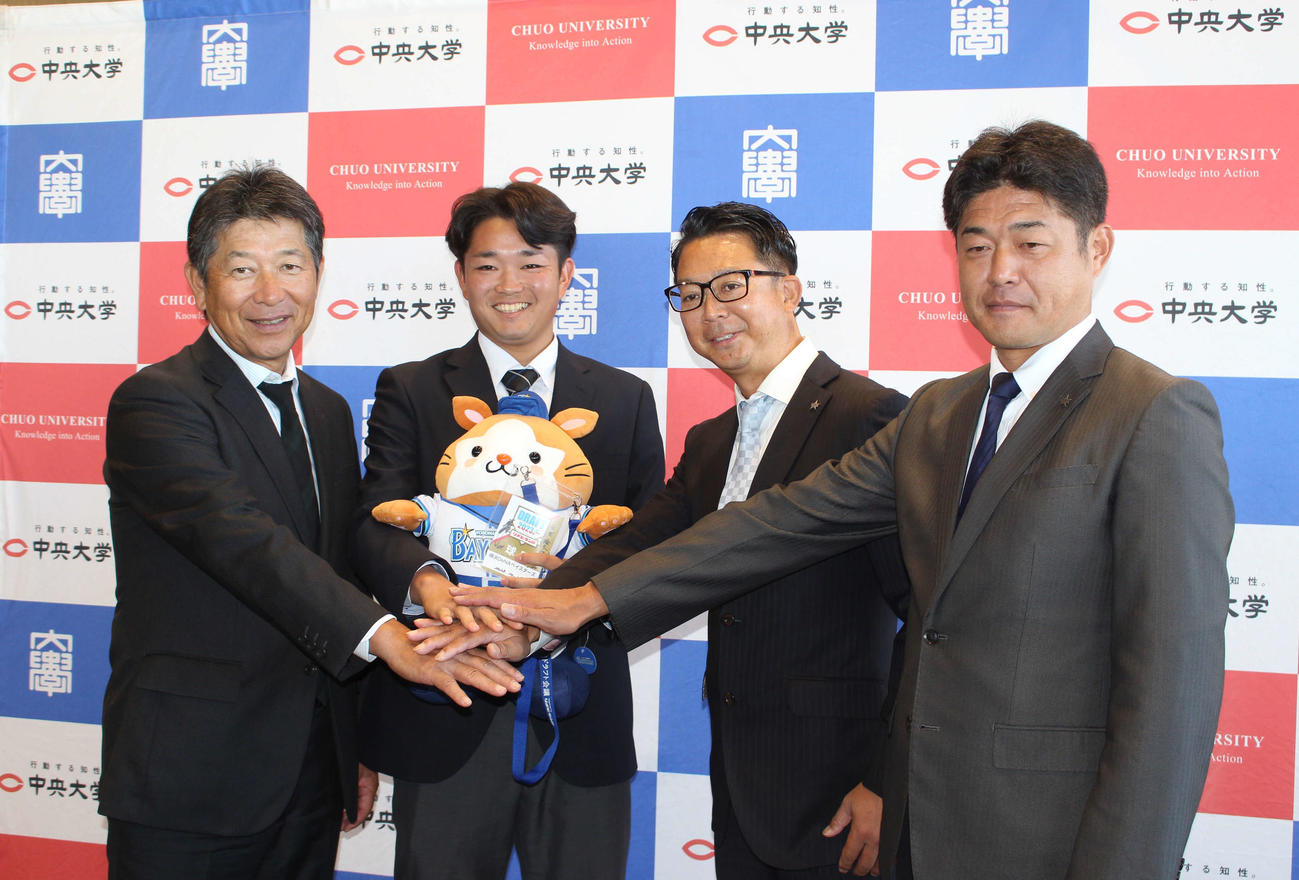 指名あいさつを受け、DB．スターマンを手に笑顔のDeNAドラフト5位の中大・石田（左から2人目）（撮影・久保賢吾）