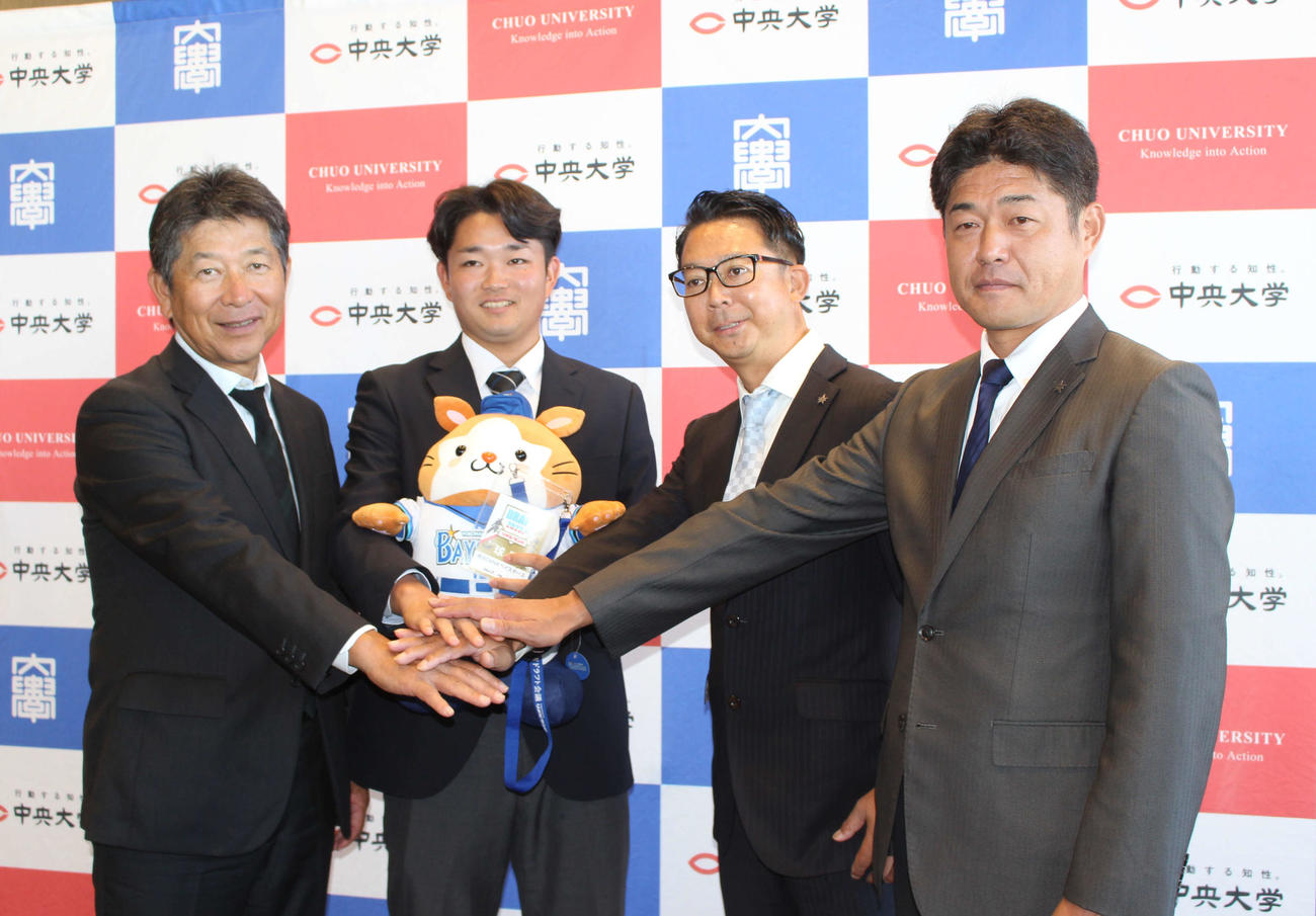 指名あいさつを受け、DB．スターマンを手に笑顔のDeNAドラフト5位の中大・石田（左から2人目）（撮影・久保賢吾）