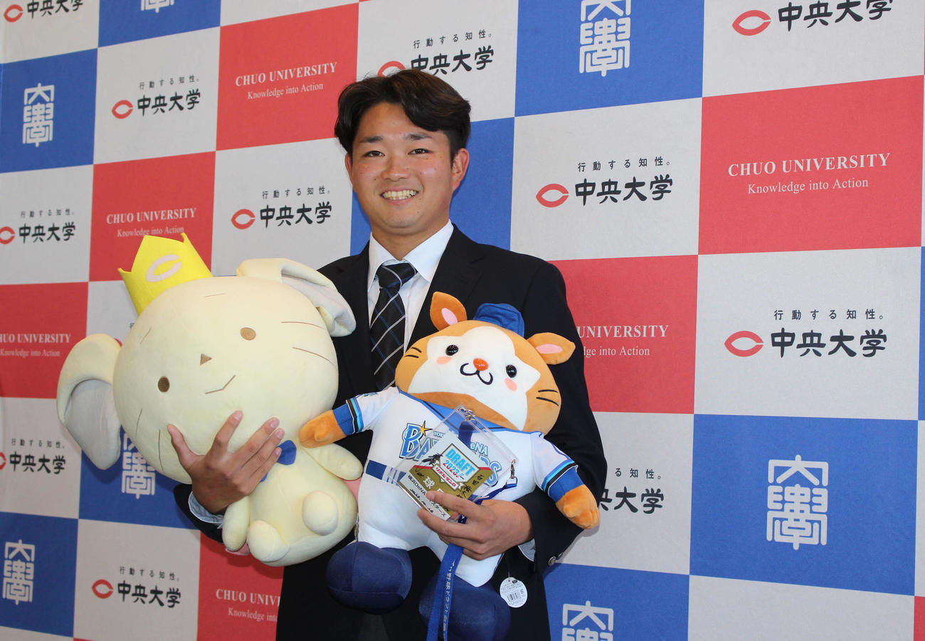 指名あいさつを受け、DB．スターマン＆チュー王子を手に笑顔のDeNAドラフト5位の中大・石田（撮影・久保賢吾）