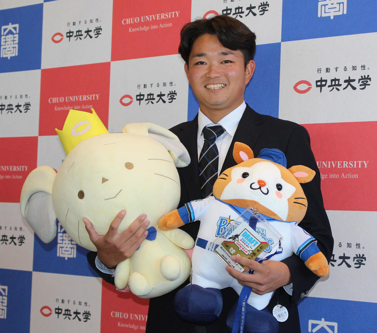 指名あいさつを受け、DB．スターマン＆チュー王子を手に笑顔のDeNAドラフト5位の中大・石田（撮影・久保賢吾）