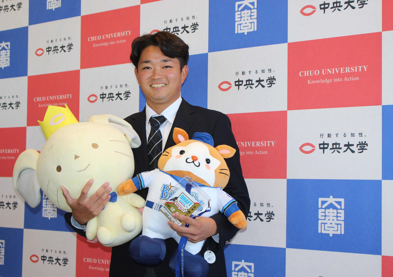 指名あいさつを受け、DB．スターマン＆チュー王子を手に笑顔のDeNAドラフト5位の中大・石田（撮影・久保賢吾）
