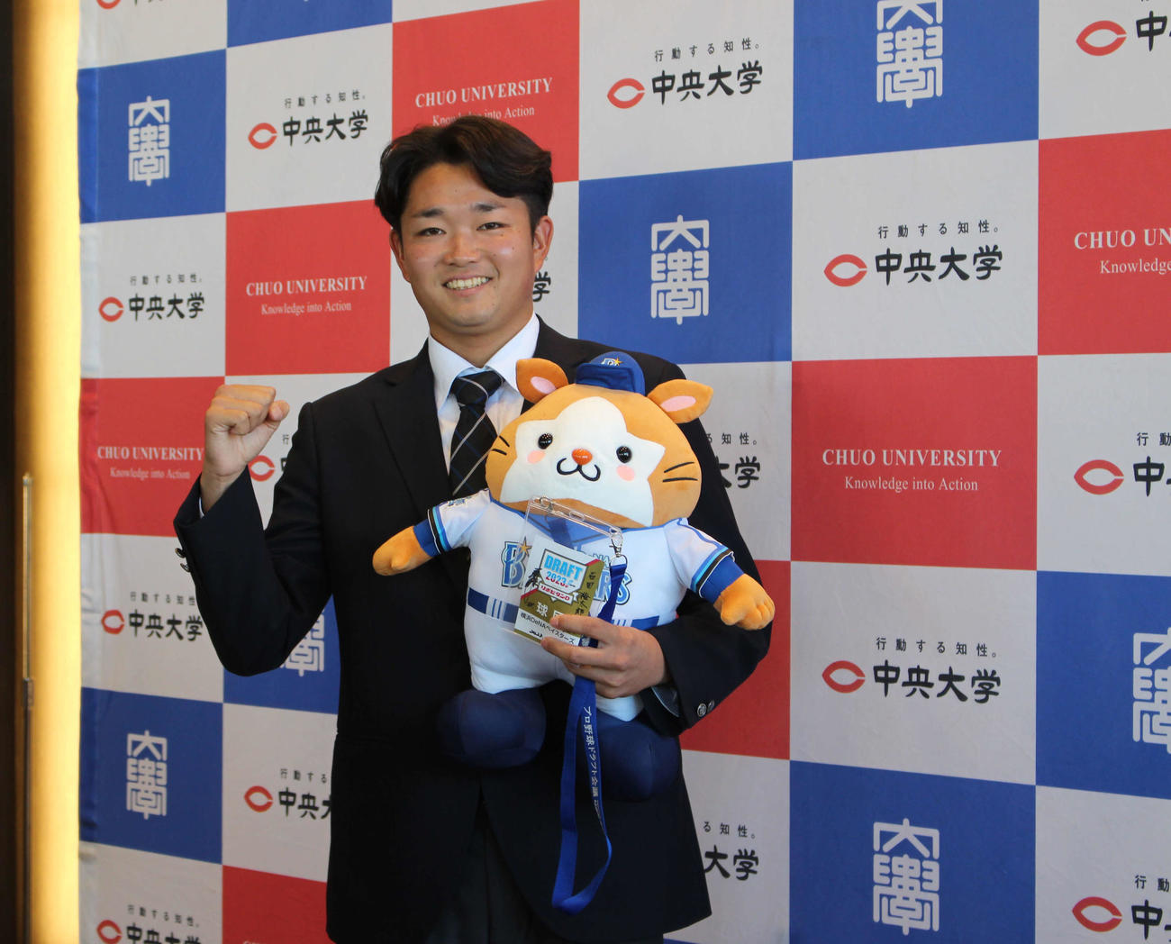 指名あいさつを受け、DB．スターマンを手に笑顔のDeNAドラフト5位の中大・石田（撮影・久保賢吾）