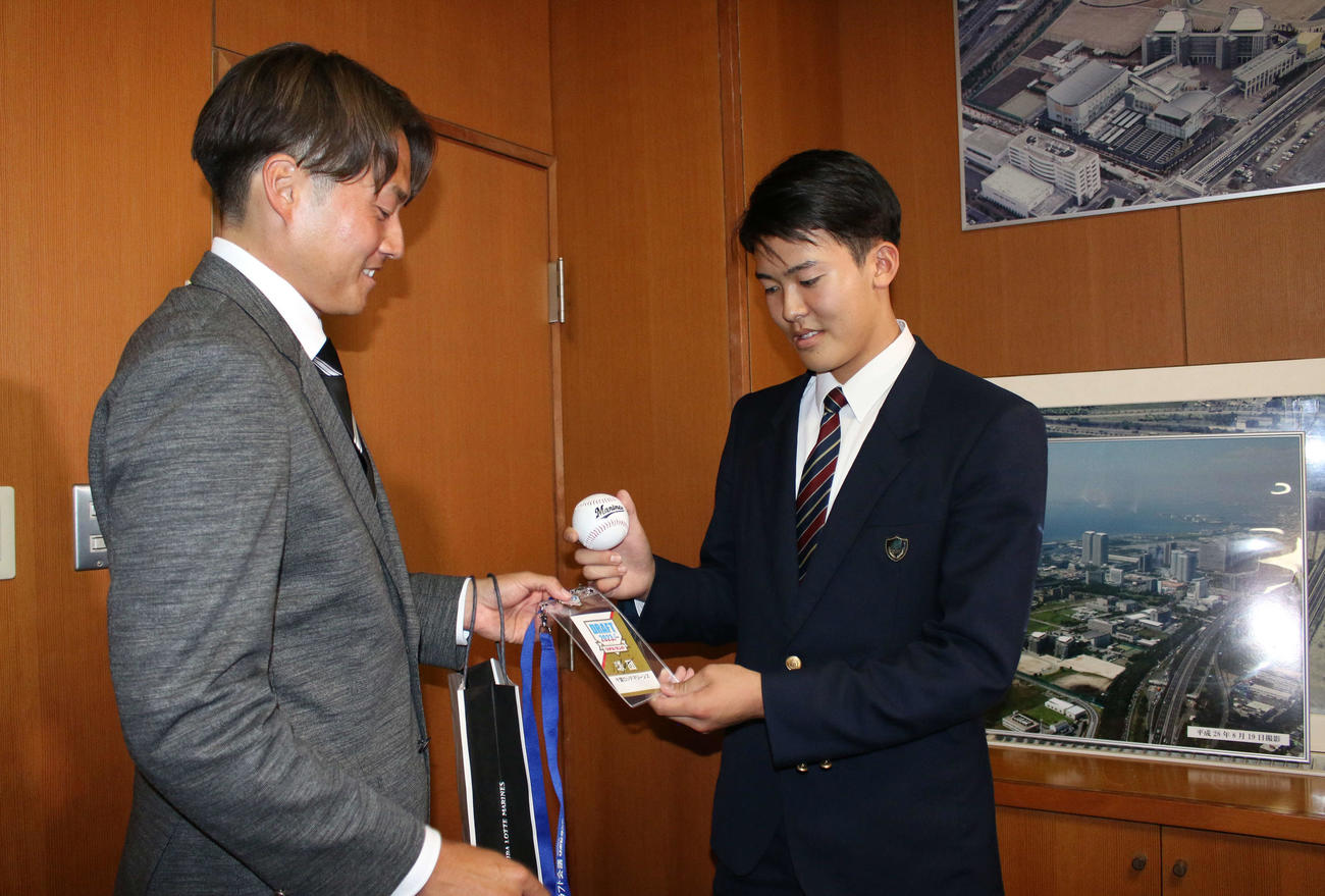 担当の有吉優樹スカウト（左）から吉井理人監督のサイン入りドラフト会場のIDなどを受け取ったロッテのドラフト4位幕張総合・早坂響投手（撮影・木下大輔）