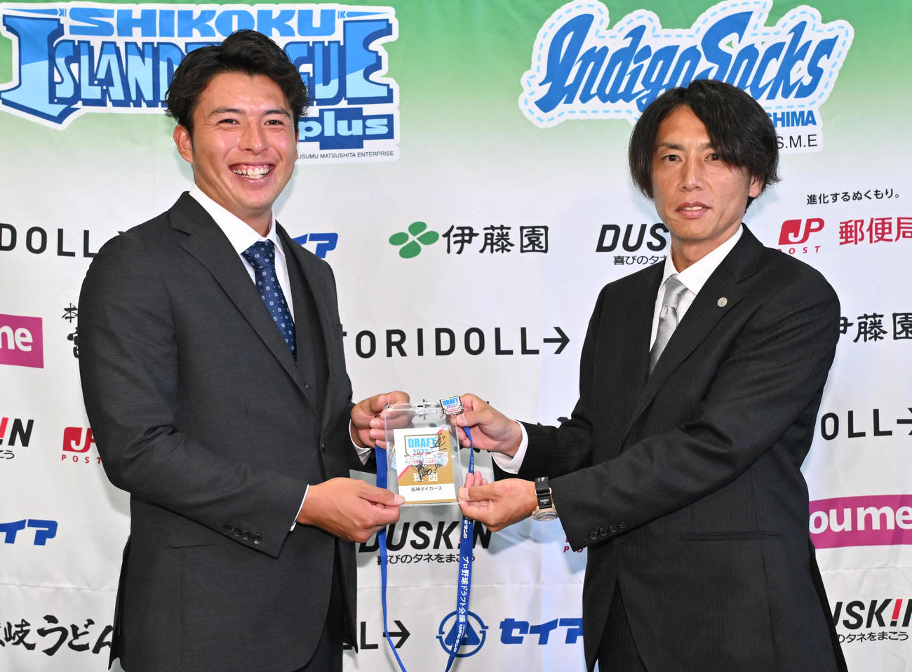 徳島インディゴソックス椎葉（左）は阪神渡辺スカウトから岡田監督のサイン入りドラフト入場証を受け取り笑顔を燃せる（撮影・石井愛子）