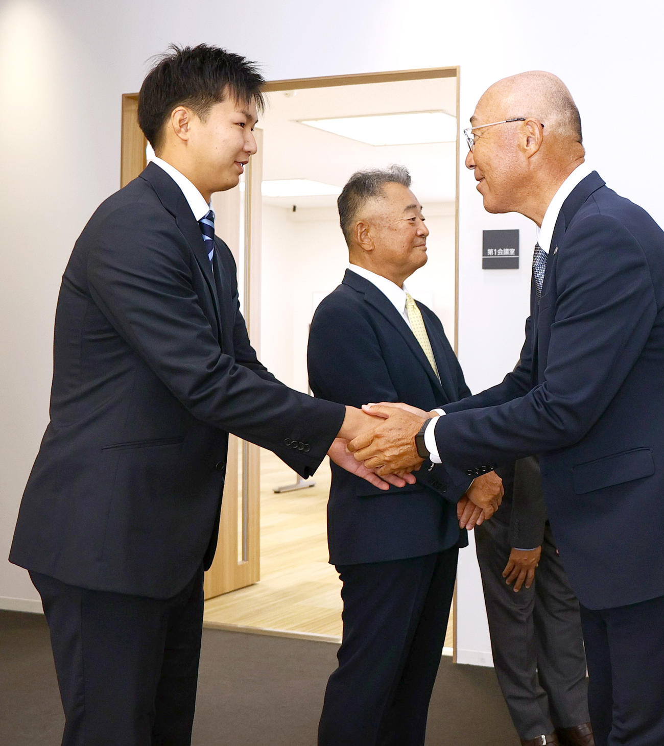 阪神ドラフト6位の大経大・津田は指名あいさつに訪れた畑山統括スカウト（右）と握手をかわす。中央は大経大・高代延博監督（撮影・上山淳一）