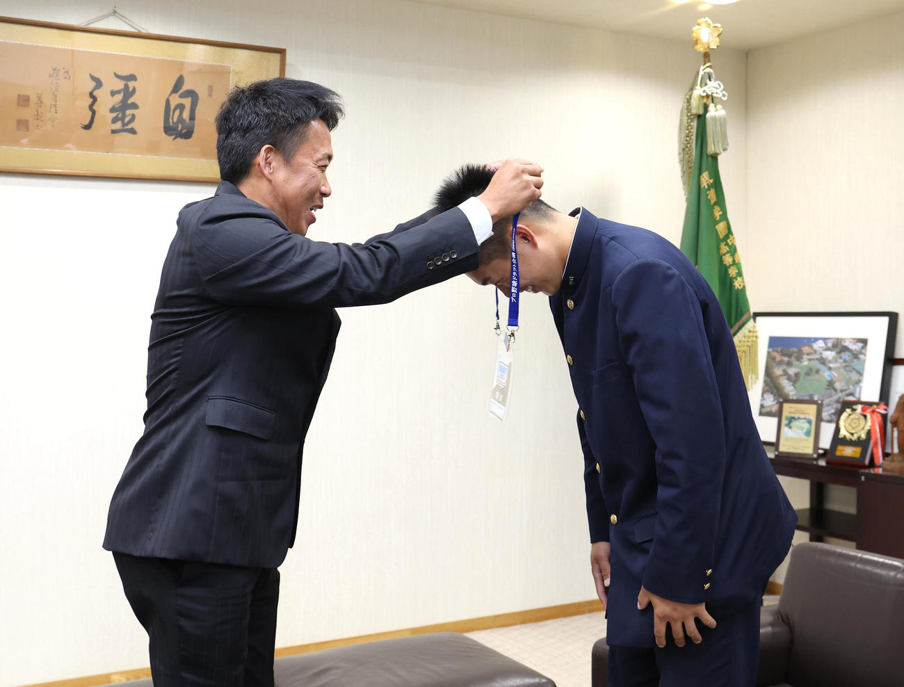 オリックス下山スカウト（左）から中嶋聡監督のサイン入場パスをかけてもらう報徳学園・堀（撮影・白石智彦）