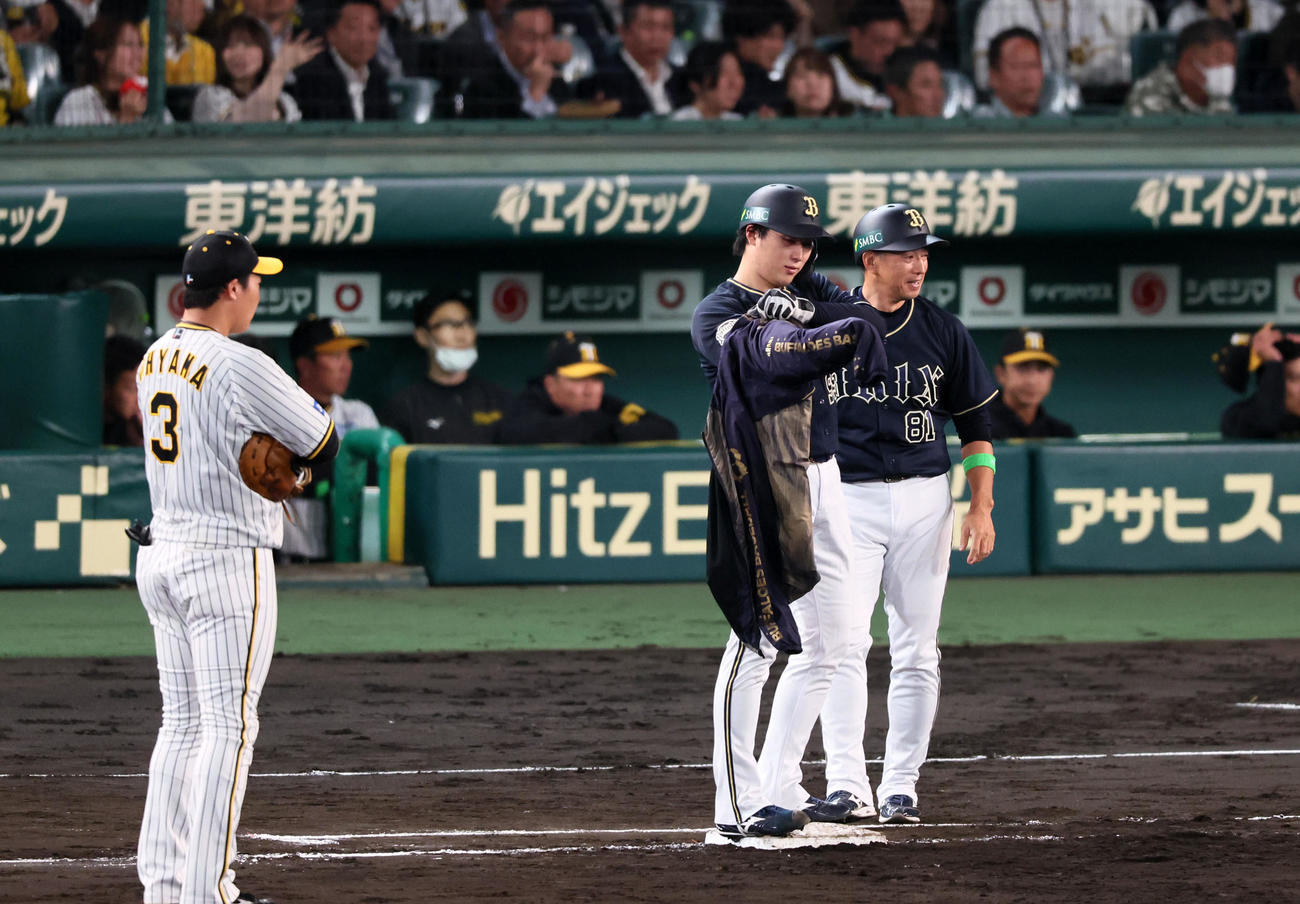 阪神対オリックス　5回表オリックス1死、一塁走者となり上着に袖を通そうとする東だが…。右は田口コーチ（撮影・加藤哉）
