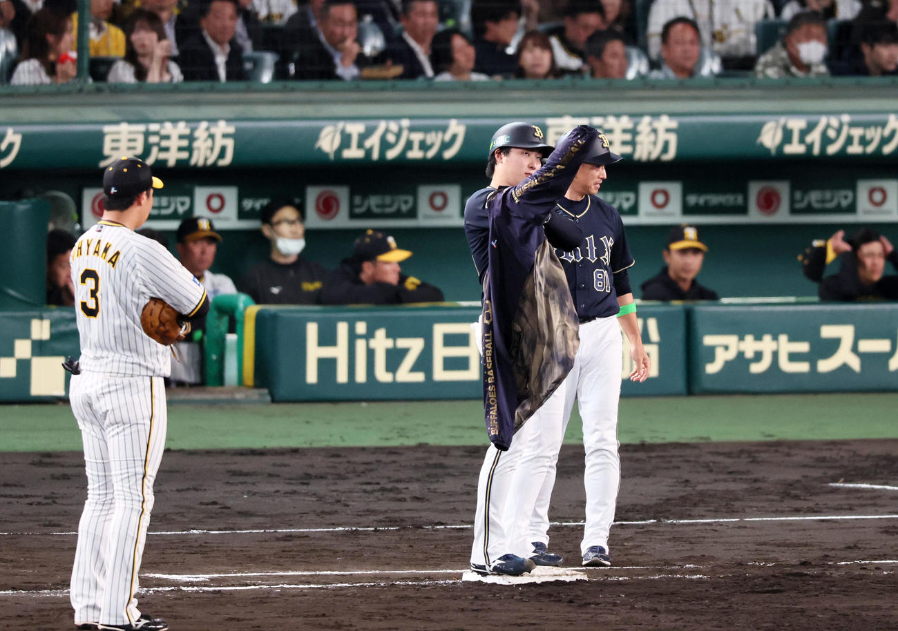 阪神対オリックス　5回表オリックス1死一、二塁、ウインドブレーカーを着るのに苦戦する一塁走者東（中央）。右は田口コーチ（撮影・加藤哉）